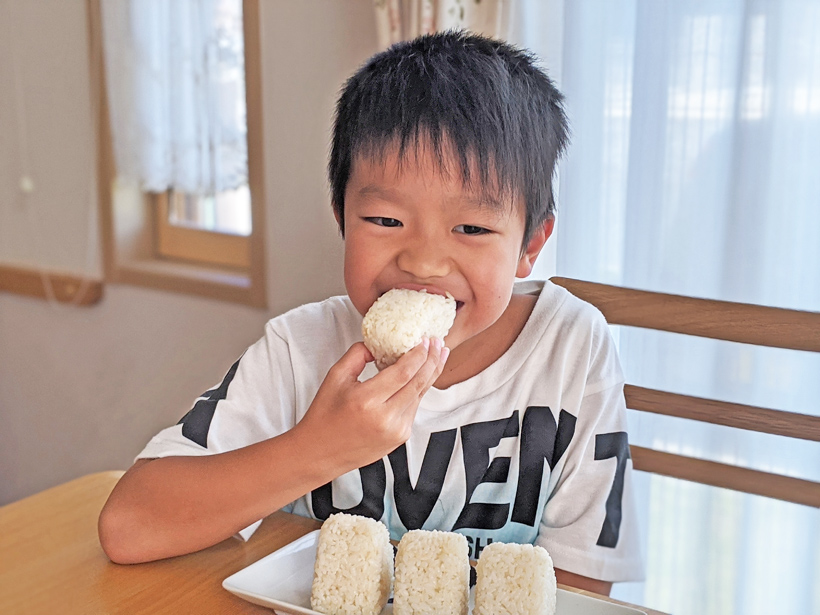 自然栽培米おにぎりを食べる子供